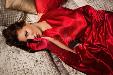 Sensual Brunette In A Red Dress Lying On The Bed Stock Photo Image Of