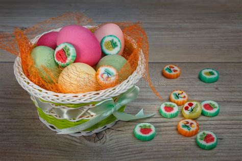 Multi Colored Easter Eggs And Sweets In A Beautiful Basket Stock Photo