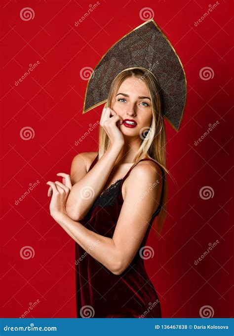 Beautiful Blonde Russian Girl In Traditional Kokoshnik Hat Velvet Festive Dress On A Red