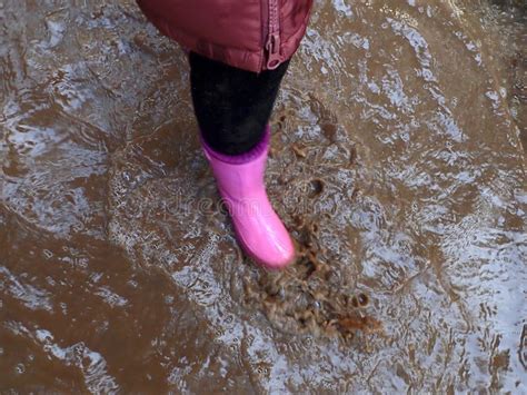 spring puddle puddle walk girl in pink rubber boots walks through the puddles spring mud and
