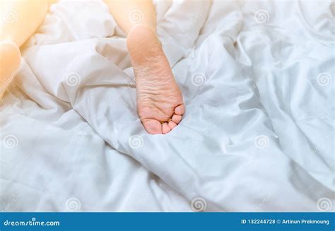 Close Up Woman Bare Feet On The Bed Over White Blanket And Bed Sheet In The Bedroom Of Home Or