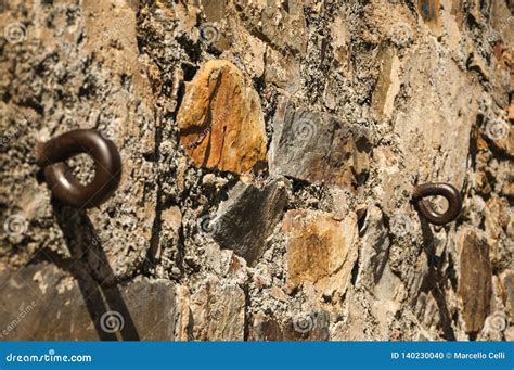 Close Up Of Two Iron Rings Stuck With Cement In An Old Stone Wall At
