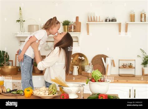 Mom Kisses Her Daughter In The Kitchen Happy Family At Home Family Healthy Life Concept Stock