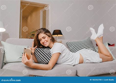 Gorgeous Young Woman In White Socks Lying On Couch And Making Selfie