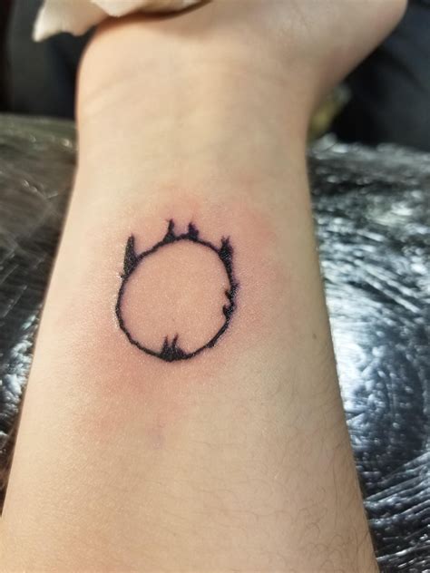 A Small Black Circle Tattoo On The Wrist