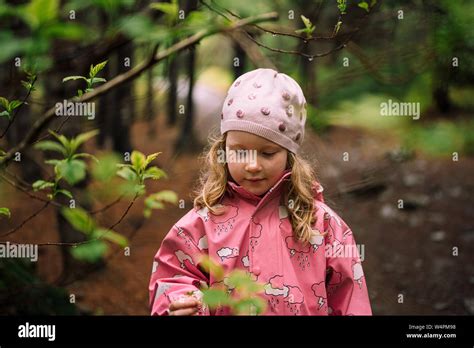 Little Blonde Girl Wearing Pink Raincoat And Hat Walking In Reykjavik