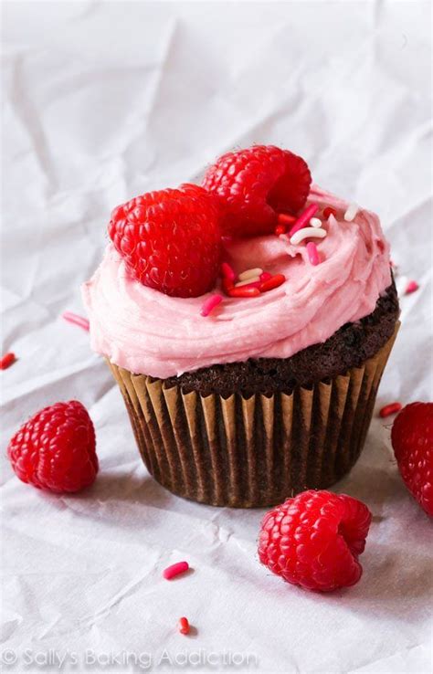 A Cupcake With Pink Frosting And Raspberries On Top