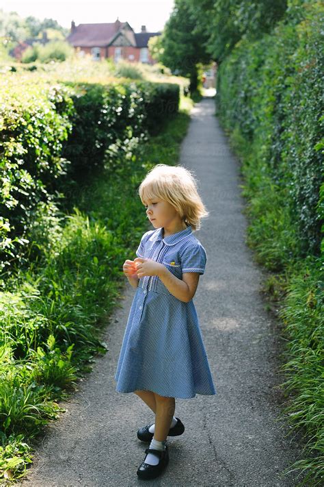 Little Girl In Summer School Uniform Stands On A Path In England By