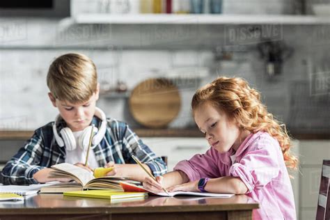 Concentrated Little Kids Doing Homework Together At Kitchen Stock