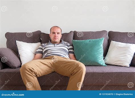 Relaxed Man Sitting On The Sofa And Looking At The Camera Stock Photo