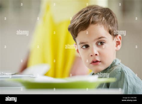 Boy Sitting At A Dining Table Stock Photo Alamy