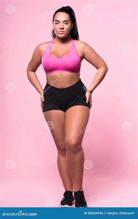 Het Prettige Mooie Mollige Vrouw Stellen Op Roze Achtergrond Stock Foto