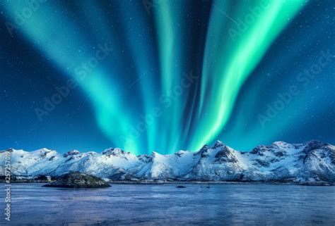 Aurora Borealis Above The Snow Covered Mountains In Lofoten Islands