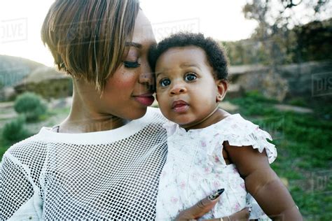 Black Mother Holding Baby Daughter In Field Stock Photo Dissolve