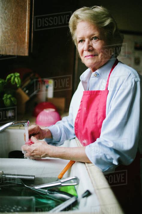 Older Woman Washing Dishes In Kitchen Sink Stock Photo Dissolve