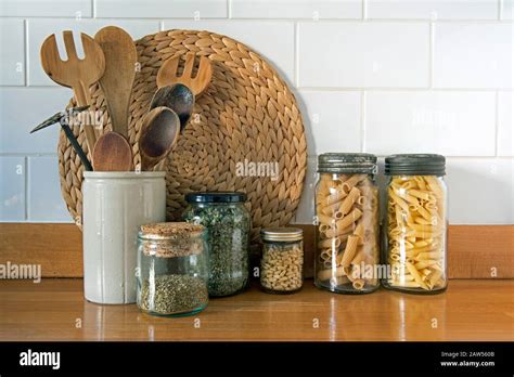 Eco Friendly Kitchen Utensils With Vintage And Recycled Glass Storage Jars Against White Tiles