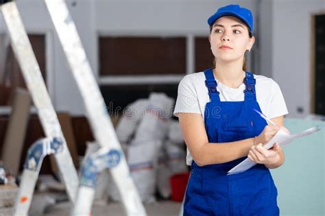 Focused Female Builder Filling Out Papers At Indoor Construction Site