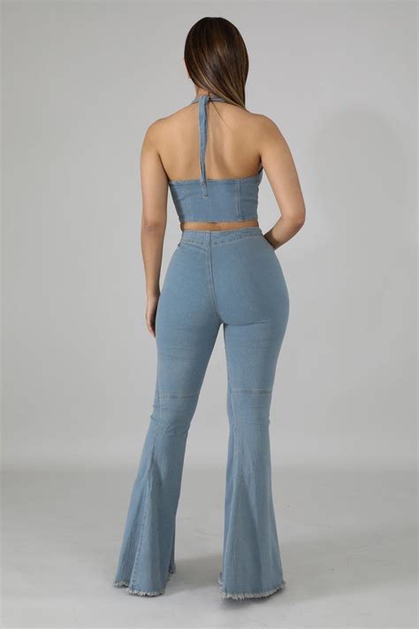 The Back View Of A Woman In Light Blue Denim Pants And Cropped Top With Her Hands On Her Hips