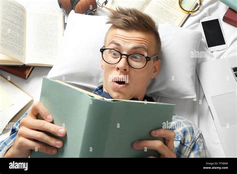 Funny Young Man Reading Book While Lying On Bed Stock Photo Alamy