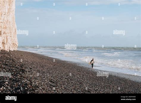 Seven Sisters, UK - October 1, 2022: Surfer with a board walking on the