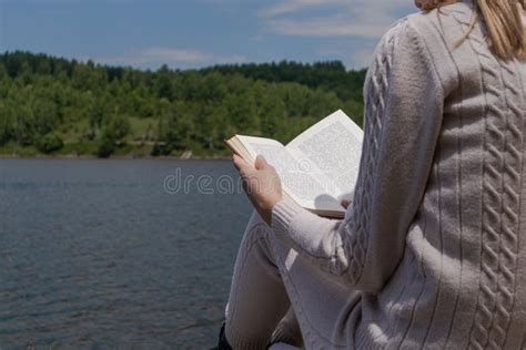 Woman With Book On Legs Lap Reading Near Lake In Nature Relaxation And