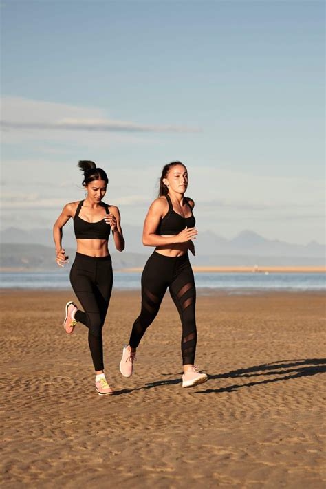 two women running on the beach in black sports bra tops and matching leggings