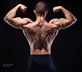 Muscular man in studio show his back - Shirtless bodybuilder in studio ...
