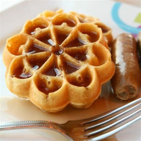 A Plate With Waffles Sausage And Jelly On It Next To A Fork