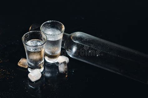 Close Up View Of Bottle And Glasses Of Vodka Standing Isolated On Black