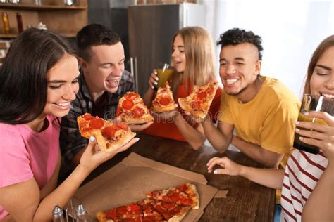 Young People Having Fun At Party With Delicious Pizza Indoors Stock