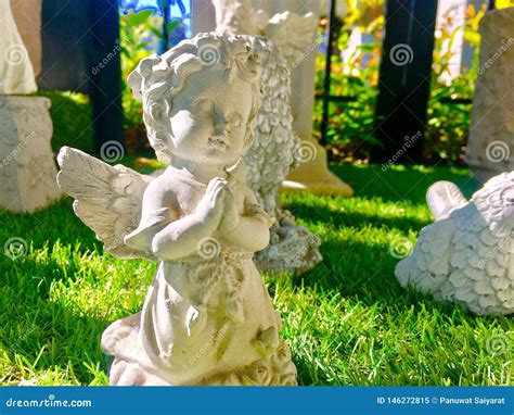 A Cute Little Angel Statue On The Grass With Sunlight Stock Image