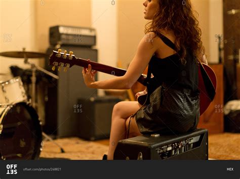 Back View Of Young Woman Playing An Electric Guitar While Seated On An