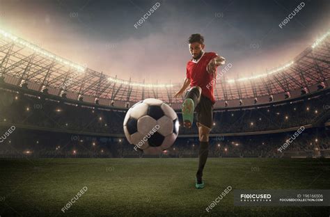 Jugador de fútbol pateando la pelota pasto deportista Stock Photo
