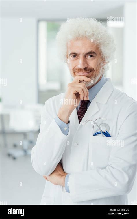 Professional Doctor Posing At Hospital And Smiling At Camera With Hand