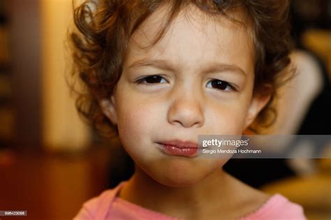 A 3 Year Old Girl With Curly Hair Looking At The Camera And Making