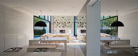 Bright White Living Space Opening Up To A Pool On One Side And A Garden