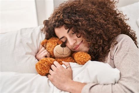 Young Hispanic Woman Hugging Teddy Bear Lying On Bed Sleeping At