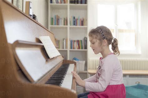 Little Girl Playing Piano At Home Stock Photo