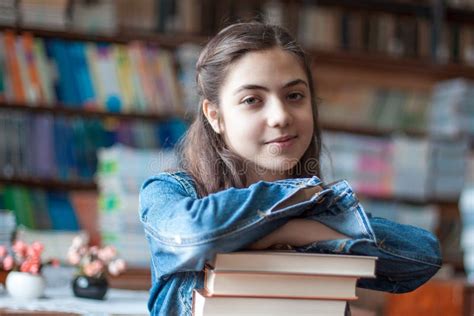 Beautiful Schoolgirl Sitting In The Library With Books Stock Photo