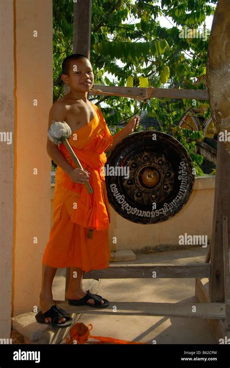 Buddhist Novice Monk Wearing An Orange Robe Hitting A Gong Wat Phonxay