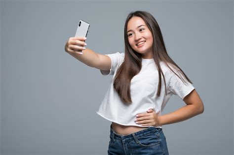 Mujer Asiática Joven Sonriente Que Toma Un Selfie Con El Teléfono Móvil Sobre Fondo Gris Aislado