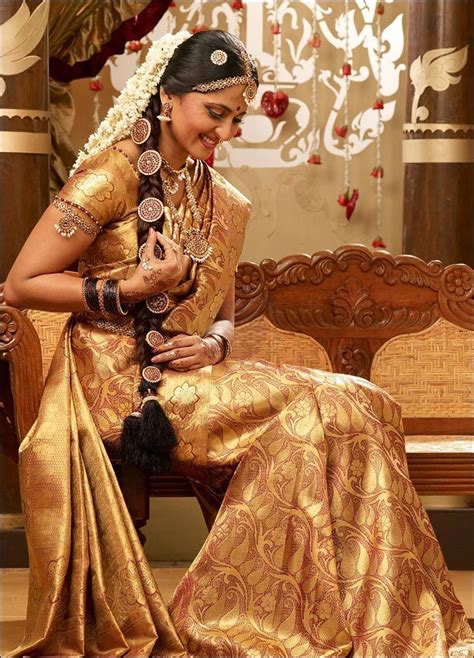 A Woman Sitting On Top Of A Wooden Bench Wearing A Gold Dress And Headpiece
