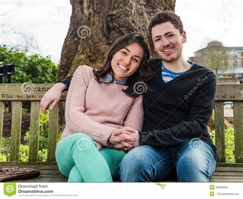 pares heterosexuales jovenes que se sientan en un banco de parque foto de archivo imagen de