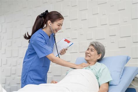 Nurse Or Doctor Is Caring For An Elderly Female Patient Lying On The