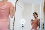 Attractive woman looking in mirror against ring lamp · Free Stock Photo
