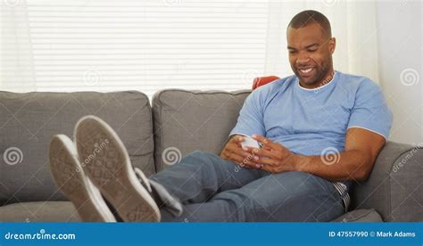 Black Man Sitting On Couch Texting Stock Photo Image Of Messaging