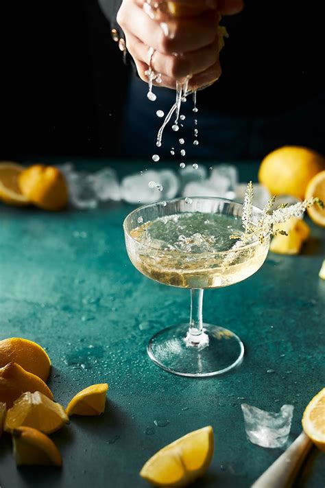 Someone Is Pouring Water Into A Martini Glass With Lemons On The Table