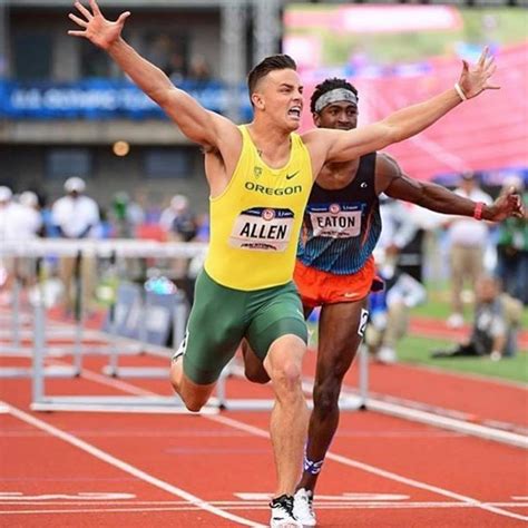 Two Men Running On A Track With Their Hands In The Air And One Man