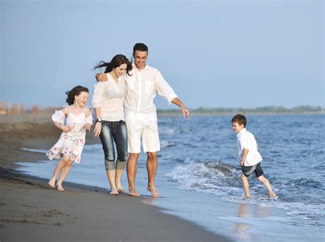 La Familia Joven Feliz Se Divierte En La Playa En La Puesta Del Sol