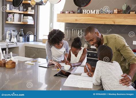 Parents Helping Children With Homework In Kitchen Stock Photo Image
